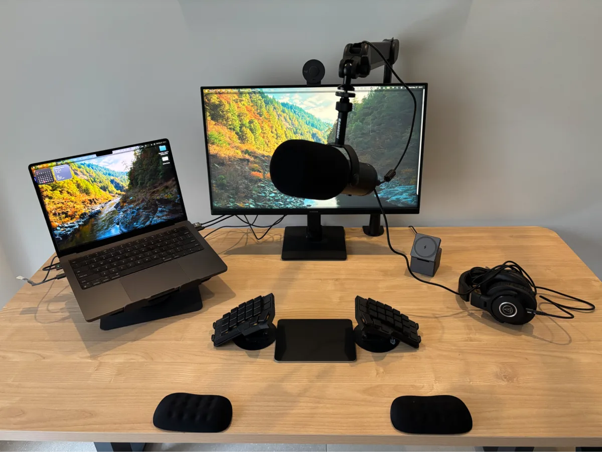 Configuración actual de escritorio con micrófono, brazo, auriculares, cámara y monitor.